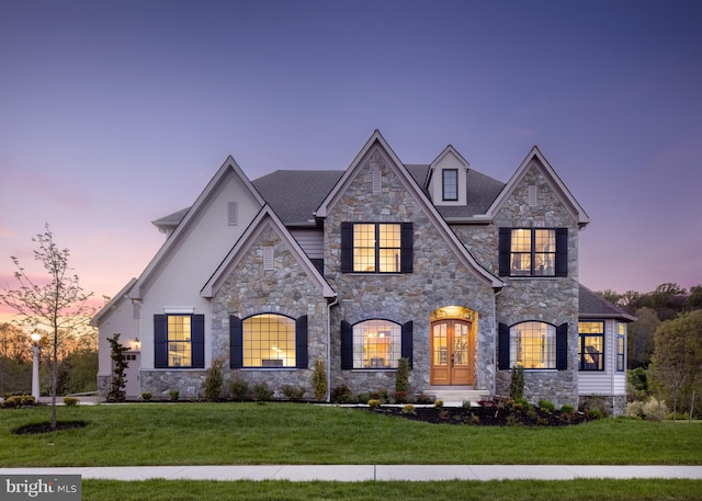 french country inspired facade with a front lawn and stucco siding