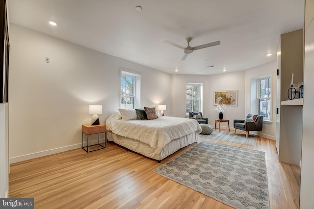 bedroom with light hardwood / wood-style flooring, ceiling fan, and multiple windows