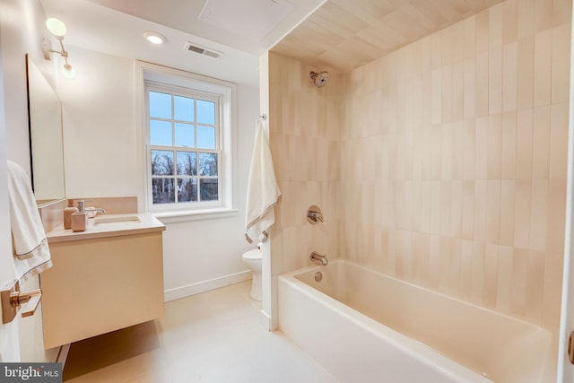 full bathroom featuring tile floors, toilet, tiled shower / bath combo, and vanity