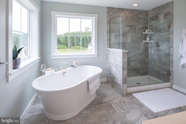 bathroom featuring a stall shower, baseboards, a freestanding tub, and recessed lighting