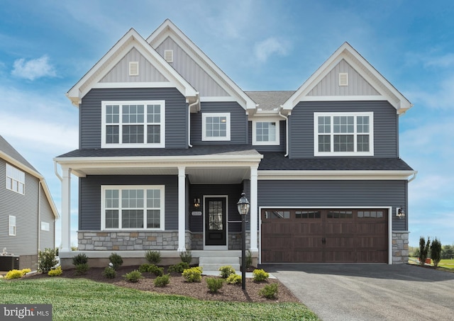 craftsman-style house with a garage, a shingled roof, stone siding, aphalt driveway, and board and batten siding