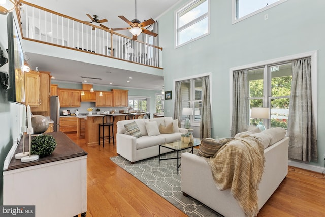 living room featuring a wealth of natural light, ceiling fan, and light wood-type flooring