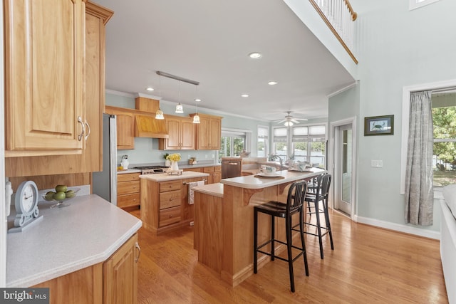 kitchen with a center island, hanging light fixtures, light hardwood / wood-style flooring, a breakfast bar area, and ceiling fan