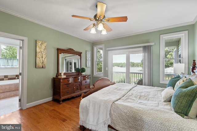 bedroom featuring ceiling fan, multiple windows, ensuite bath, and ornamental molding