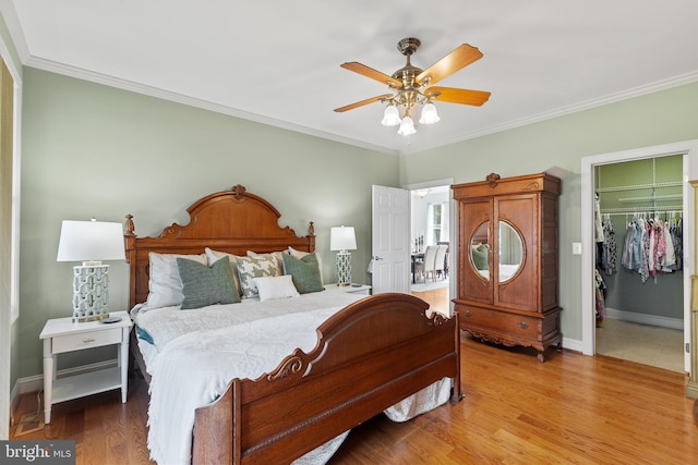 bedroom featuring a closet, ceiling fan, tile flooring, a walk in closet, and ornamental molding