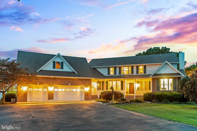 view of front of home featuring covered porch, a garage, and a yard