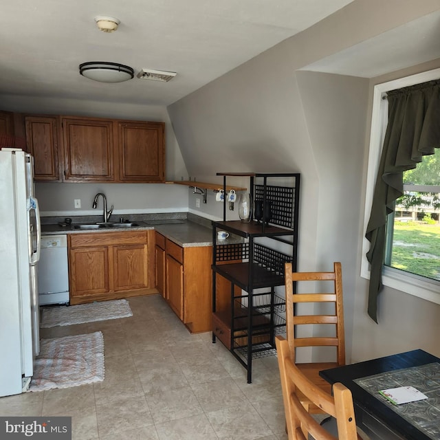 kitchen featuring sink, white appliances, light tile floors, and lofted ceiling