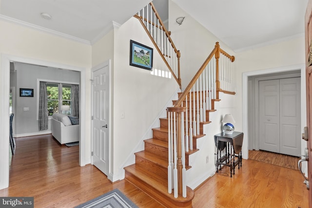 staircase with crown molding and wood-type flooring