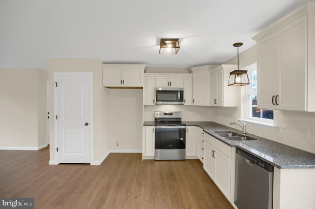 kitchen featuring light wood-type flooring, sink, stainless steel appliances, and hanging light fixtures