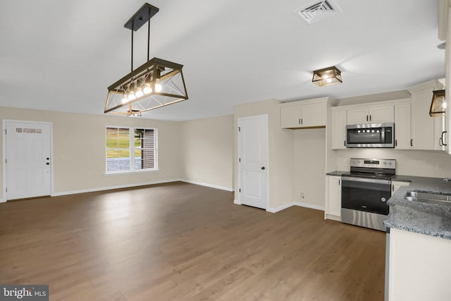 kitchen with dark hardwood / wood-style floors, pendant lighting, white cabinetry, sink, and stainless steel appliances