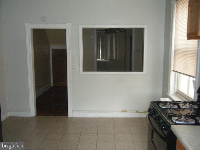 kitchen with light tile patterned flooring, a wealth of natural light, and black range with gas cooktop