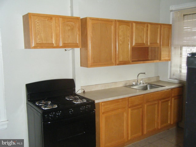 kitchen with light tile patterned floors, refrigerator, sink, and gas stove