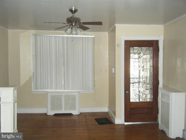 foyer entrance with ceiling fan, dark wood-type flooring, and radiator heating unit