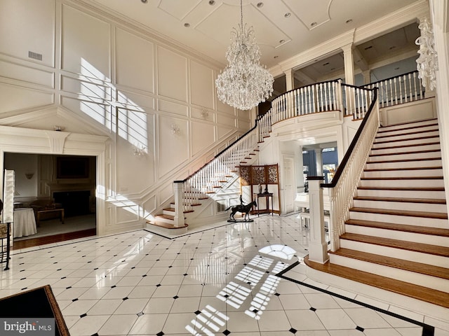 staircase featuring a towering ceiling, crown molding, and a chandelier