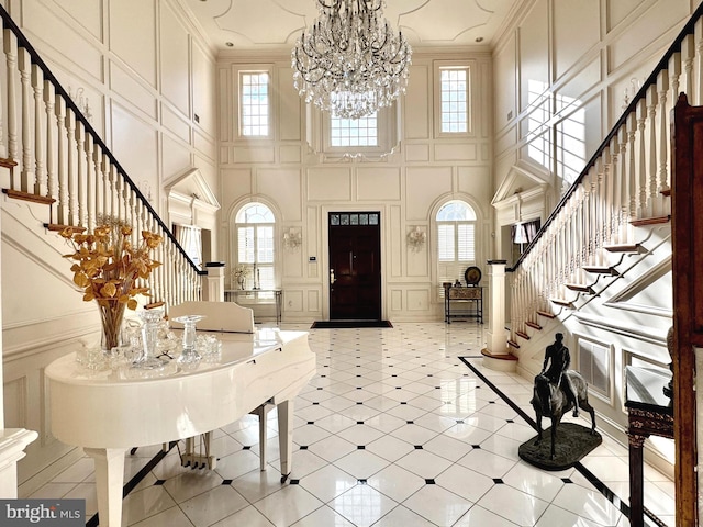 foyer entrance featuring ornamental molding, a towering ceiling, and an inviting chandelier