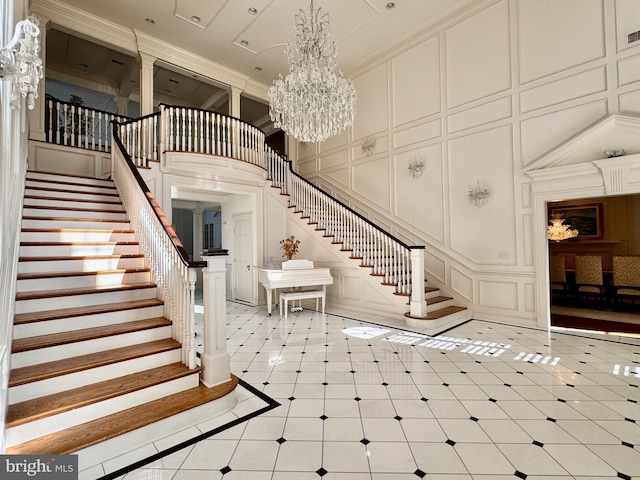 foyer entrance featuring a notable chandelier, crown molding, and a high ceiling