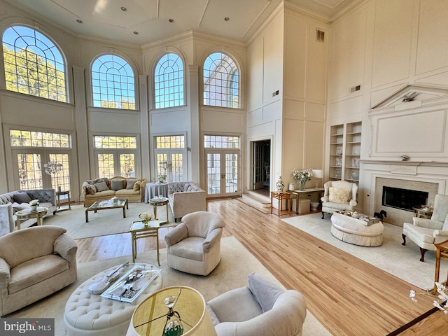 living room featuring a towering ceiling, built in features, light hardwood / wood-style floors, and a wealth of natural light