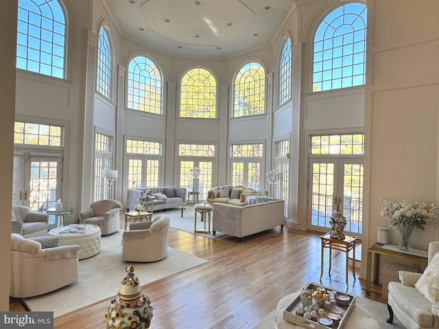 living room with light hardwood / wood-style floors, crown molding, and a high ceiling