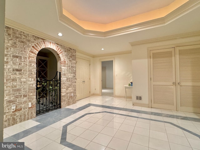 tiled empty room featuring a raised ceiling and crown molding