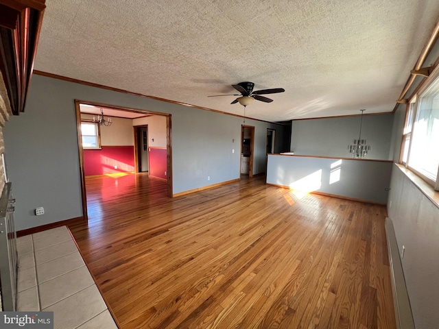 spare room with ornamental molding, ceiling fan with notable chandelier, a wealth of natural light, and light wood-type flooring