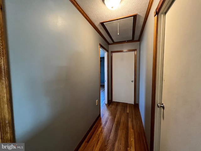 hallway with a textured ceiling, crown molding, and dark wood-type flooring