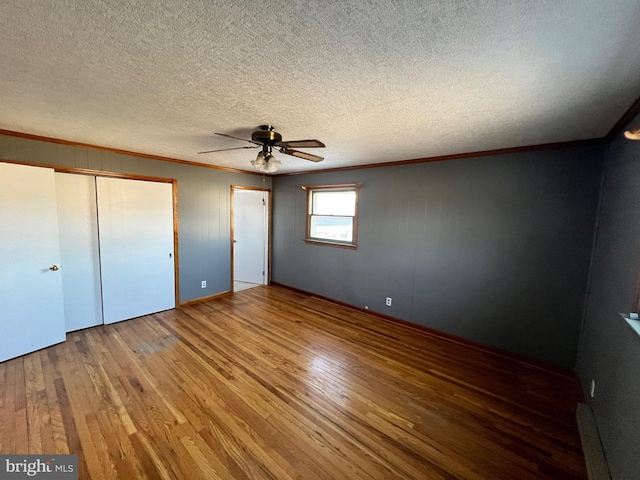 unfurnished bedroom with hardwood / wood-style floors, a textured ceiling, crown molding, and ceiling fan