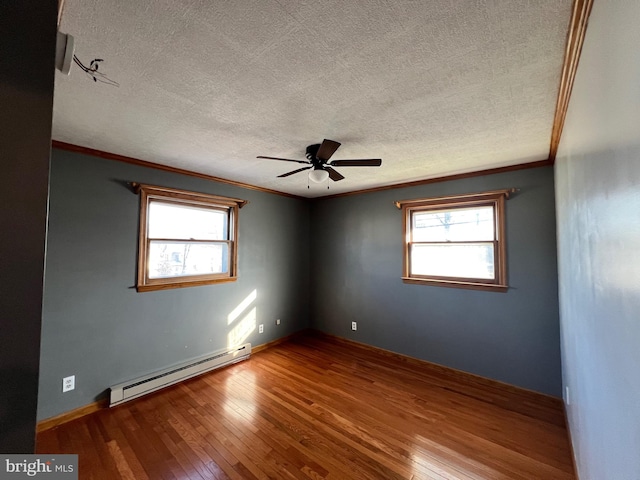 empty room with hardwood / wood-style floors, ceiling fan, a wealth of natural light, and baseboard heating