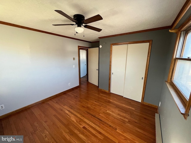 unfurnished bedroom with ceiling fan, a closet, multiple windows, and wood-type flooring