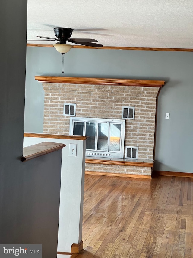 room details with ceiling fan, a textured ceiling, ornamental molding, and wood-type flooring