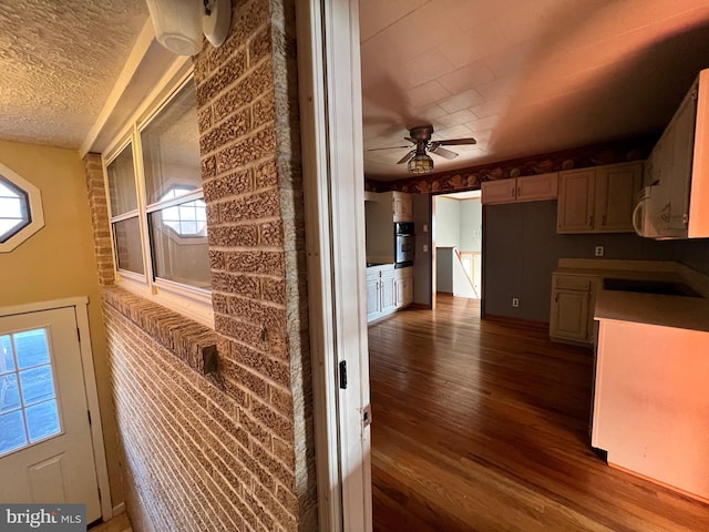 kitchen with oven, cooktop, ceiling fan, a textured ceiling, and dark hardwood / wood-style flooring