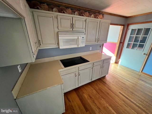 kitchen featuring black electric stovetop, ornamental molding, white cabinetry, and light hardwood / wood-style floors