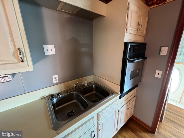 kitchen with sink, light wood-type flooring, and oven