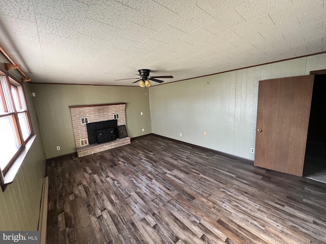 unfurnished living room with dark hardwood / wood-style flooring, wood walls, a brick fireplace, ceiling fan, and lofted ceiling