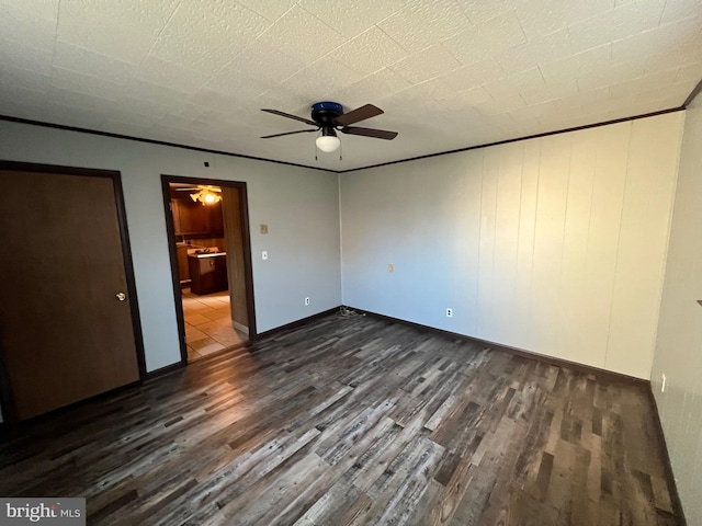 unfurnished bedroom featuring crown molding, ceiling fan, and dark wood-type flooring