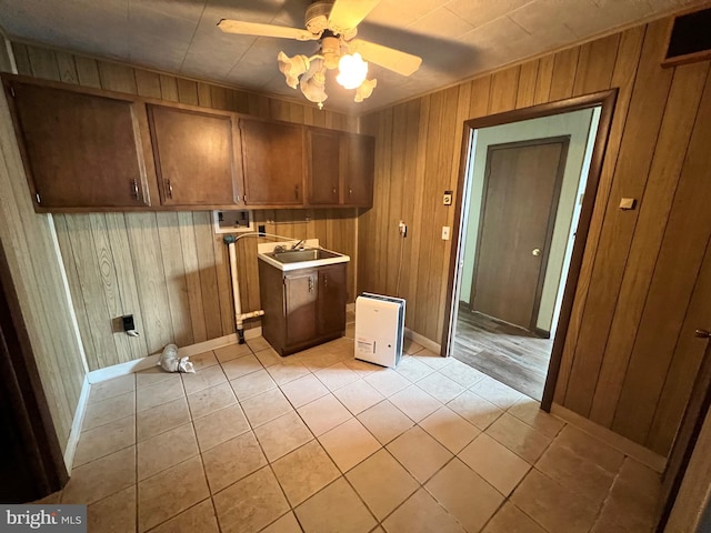 interior space featuring light tile floors, wood walls, ceiling fan, and sink