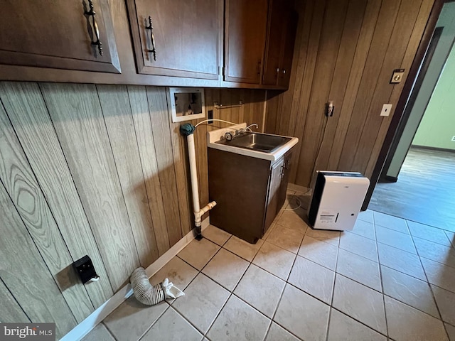 laundry room featuring wood walls, light tile floors, washer hookup, cabinets, and sink