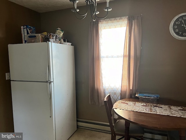 kitchen with a notable chandelier, baseboard heating, white fridge, and light tile floors