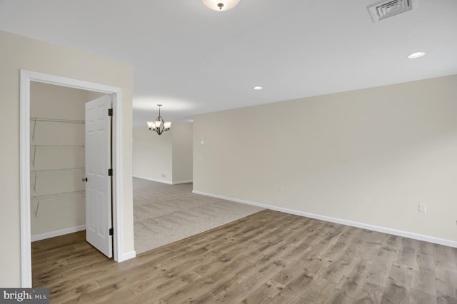 spare room featuring light hardwood / wood-style floors and a chandelier