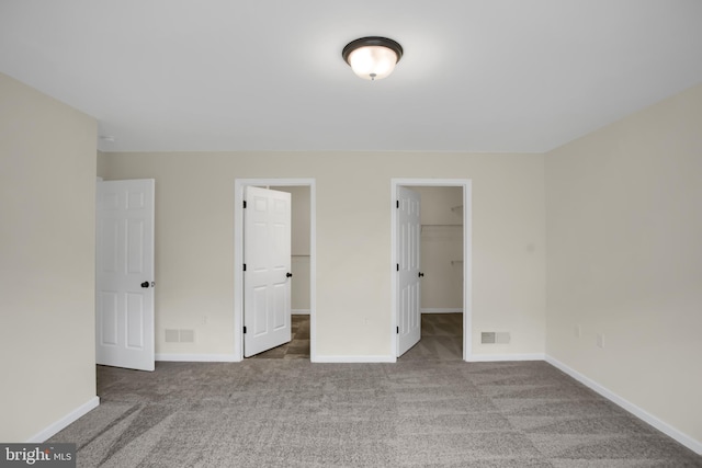 unfurnished bedroom with carpet flooring, a spacious closet, and a closet