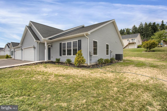 view of front of home featuring a garage, a front lawn, and central AC unit