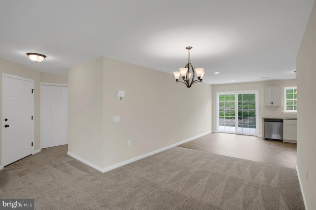 empty room featuring light carpet and a chandelier