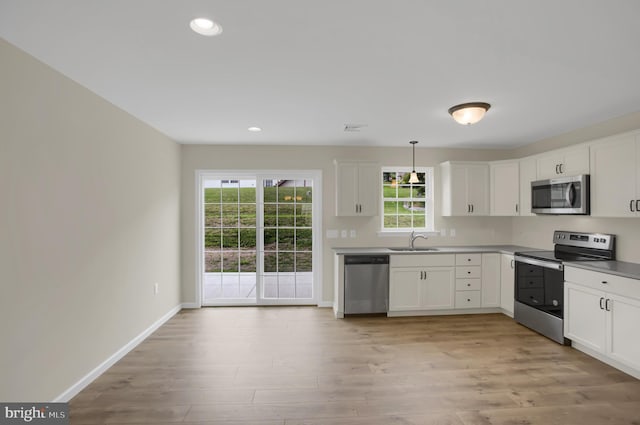 kitchen with sink, stainless steel appliances, hanging light fixtures, and white cabinets