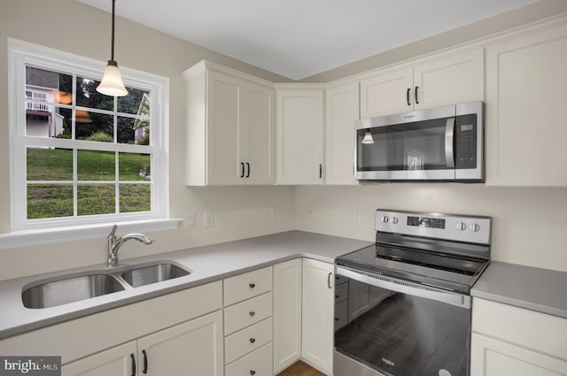 kitchen featuring white cabinetry, sink, pendant lighting, and stainless steel appliances