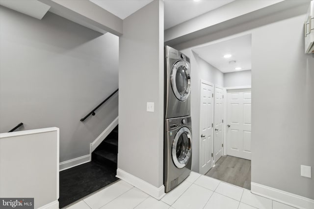 laundry area with light tile flooring and stacked washer and dryer