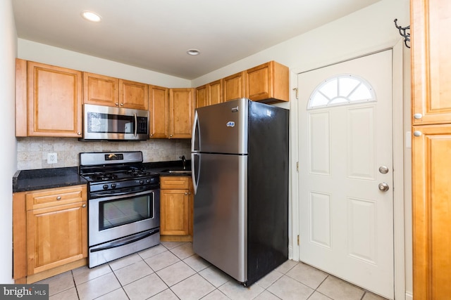 kitchen with backsplash, appliances with stainless steel finishes, light tile floors, and sink