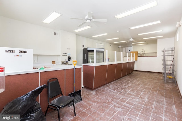 kitchen with white fridge, kitchen peninsula, ceiling fan, and light tile floors