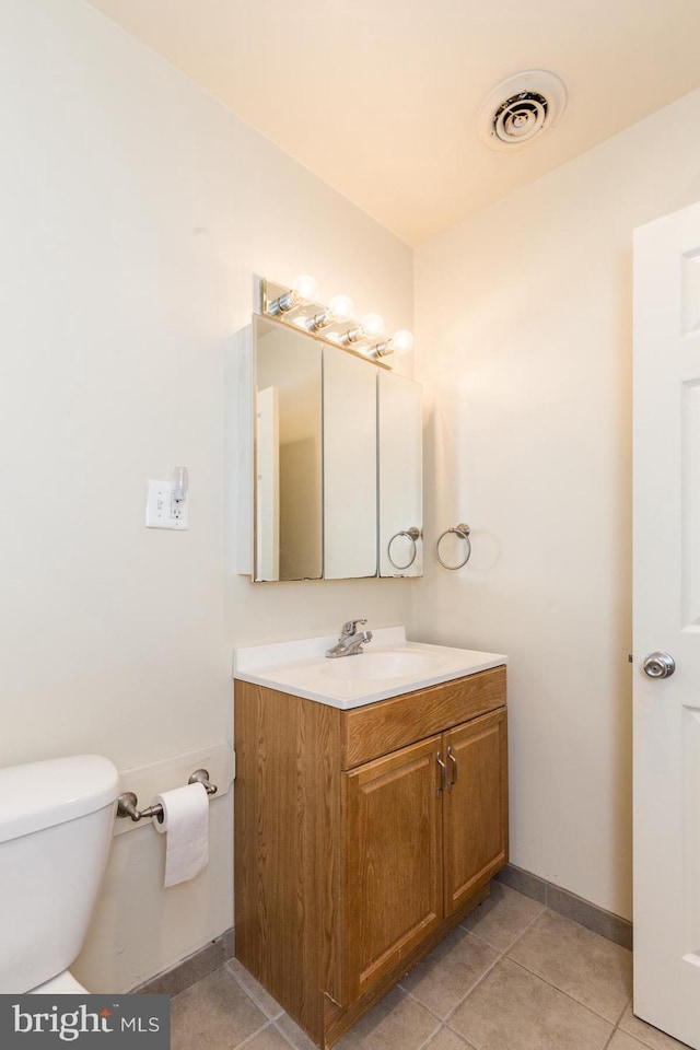 bathroom with toilet, vanity, and tile flooring