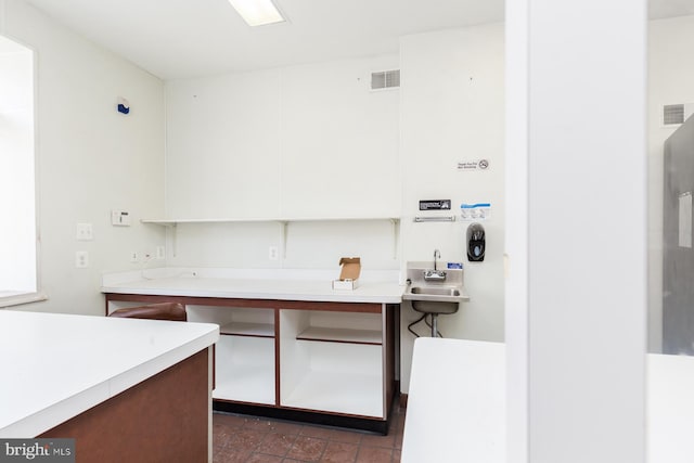 kitchen featuring white cabinets, dark tile floors, and sink