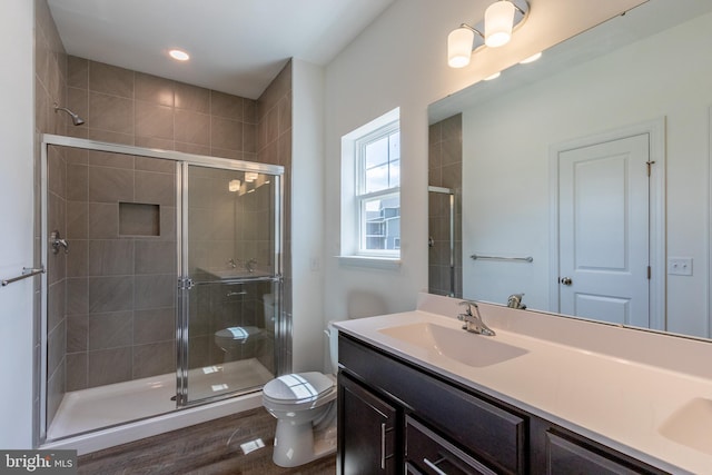 bathroom with wood-type flooring, vanity, toilet, and an enclosed shower