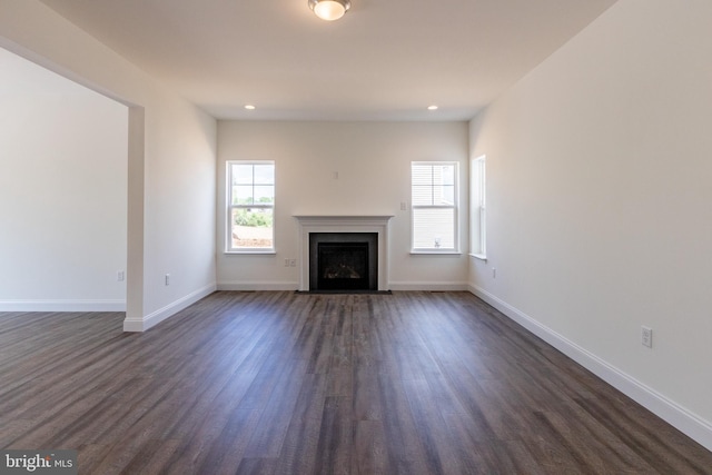 unfurnished living room featuring a healthy amount of sunlight and dark hardwood / wood-style flooring